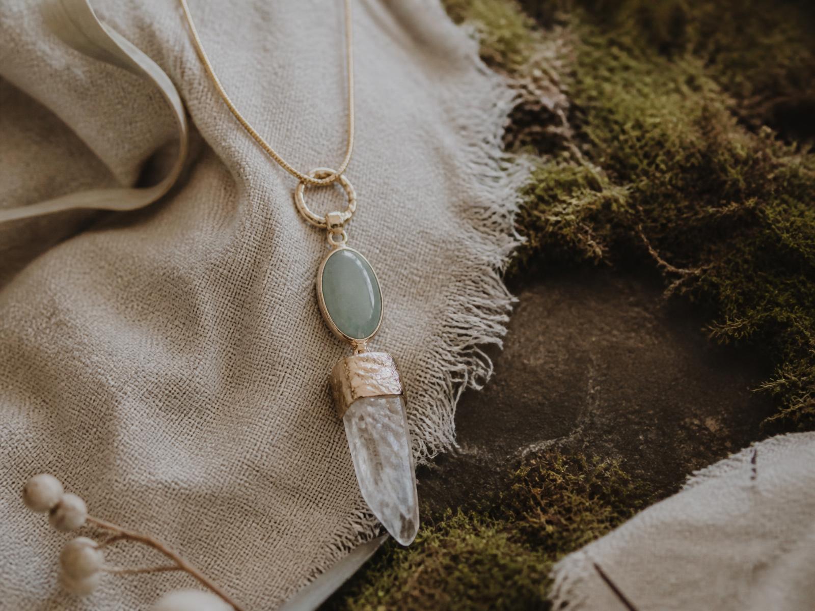 Handmade gemstone pendant necklace resting on natural linen and moss
